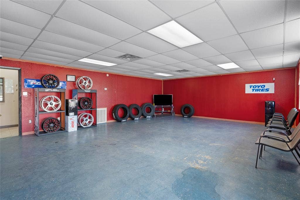 807 W Corsicana Street, Athens, TX 75751 Spacious commercial interior with textured red walls, drop ceiling with integrated lighting, and blue-toned flooring