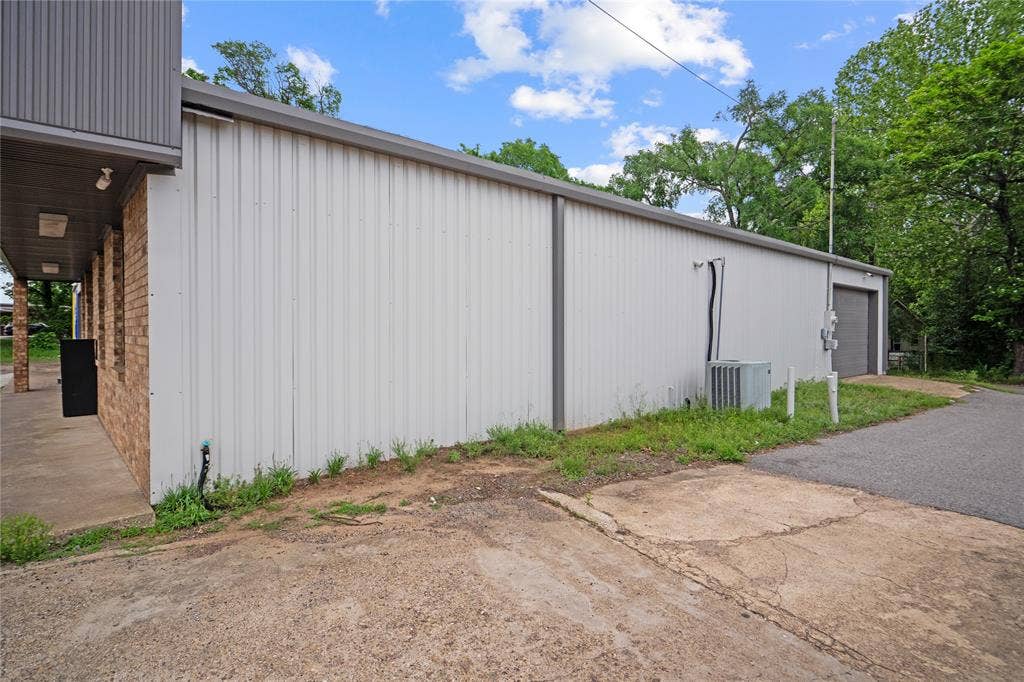 807 W Corsicana Street, Athens, TX 75751 Commercial building featuring a brick facade with a grey metal awning, a metal roll-up door, and an exterior HVAC unit