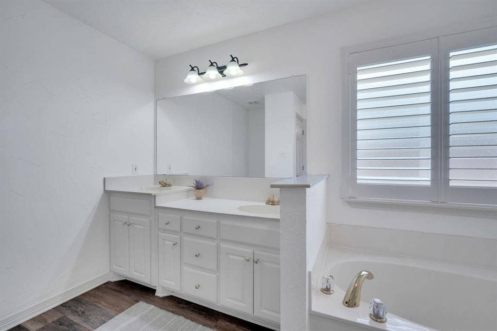 506 Whitney Drive, Midlothian, TX 76065 Bathroom featuring a dual vanity with white cabinetry, a large wall-mounted mirror, and a built-in tub with an integrated deck