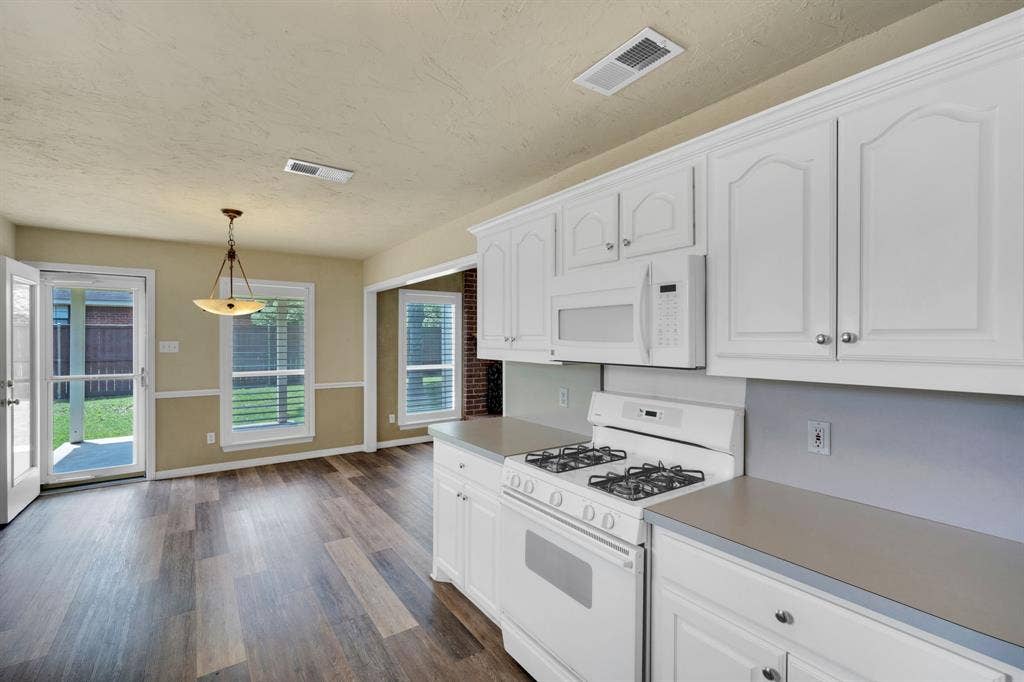 506 Whitney Drive, Midlothian, TX 76065 Kitchen with white cabinetry, gas range, and wood-finish flooring