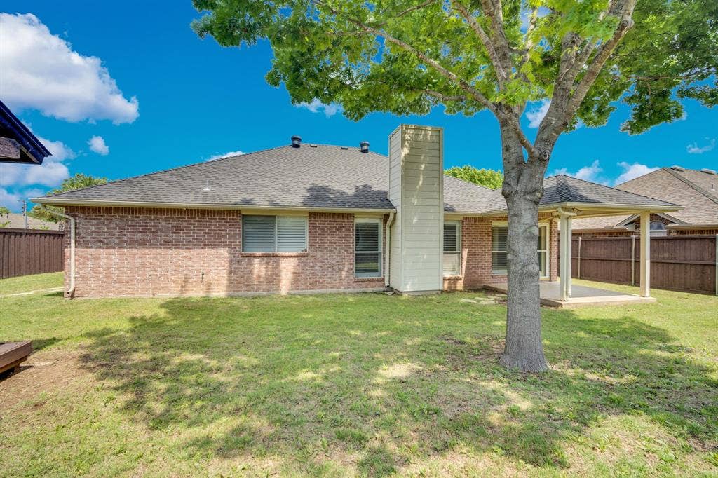 506 Whitney Drive, Midlothian, TX 76065 Expansive backyard featuring a covered patio, brick exterior, shingled roof, and a mature shade tree
