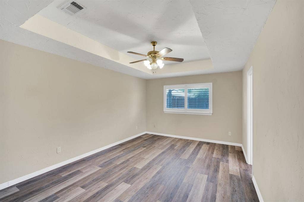 506 Whitney Drive, Midlothian, TX 76065 Spacious Primary room featuring a tray ceiling, wood-finish flooring, and a ceiling fan with light fixture
