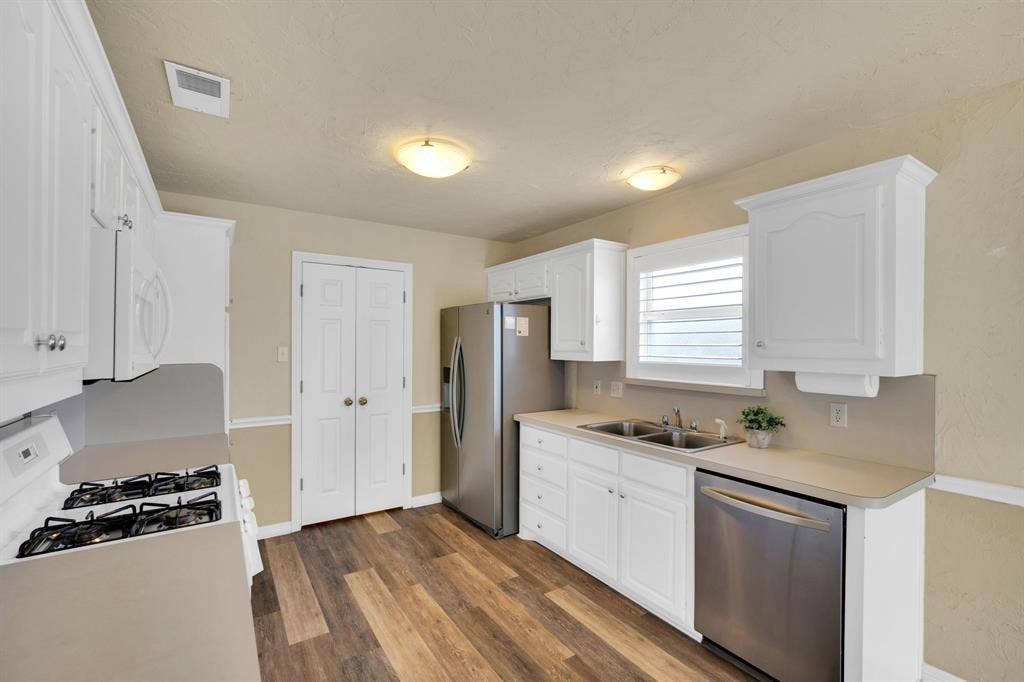 506 Whitney Drive, Midlothian, TX 76065 Bright kitchen featuring white cabinetry, light-toned countertops, a stainless steel refrigerator, and wood-finish flooring