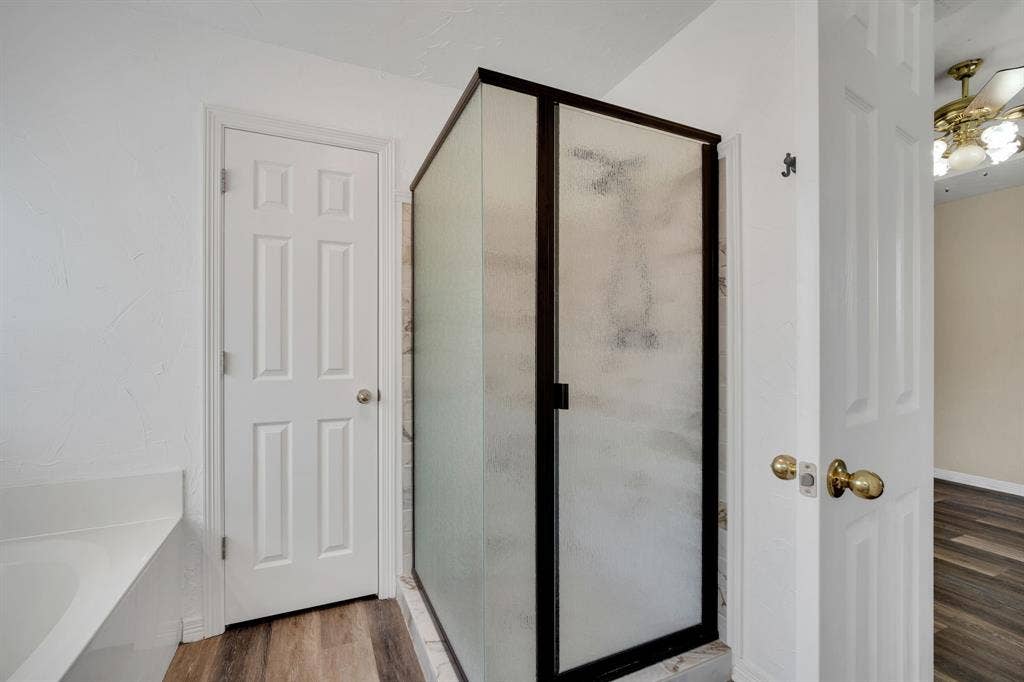 506 Whitney Drive, Midlothian, TX 76065 Enclosed shower with frosted glass panels and dark frame, positioned on wood-finish flooring