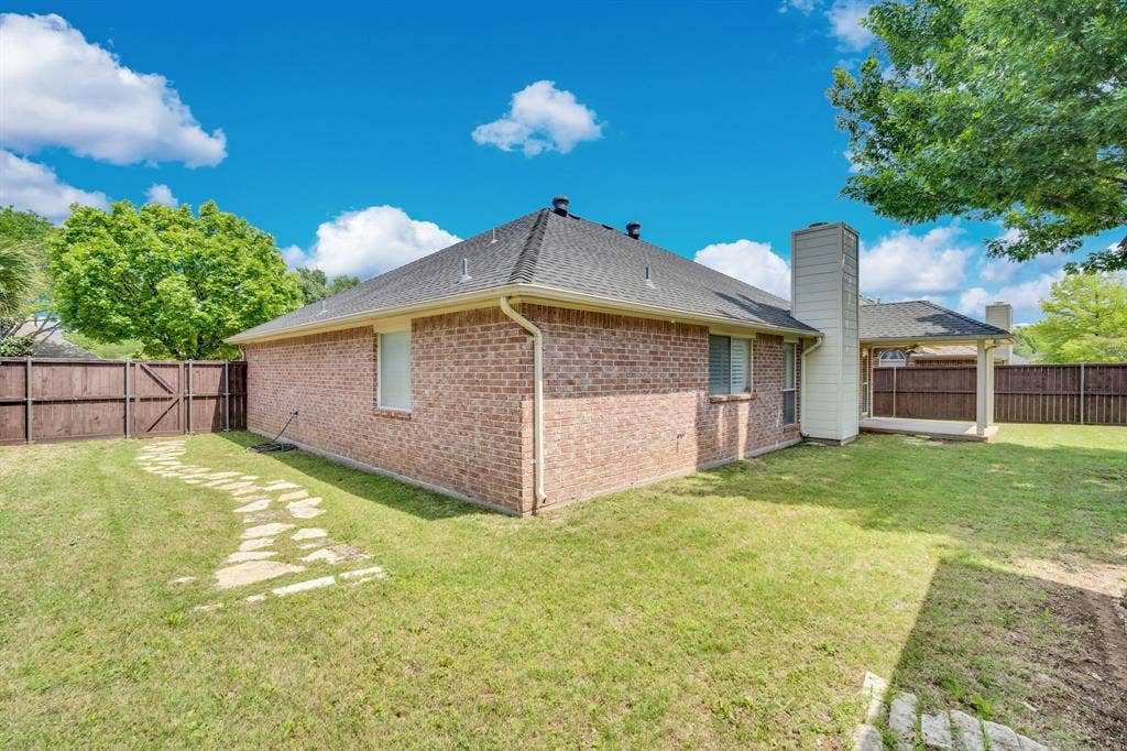 506 Whitney Drive, Midlothian, TX 76065 Expansive grassy yard featuring a stone pathway, privacy fencing, brick exterior, and a covered patio area