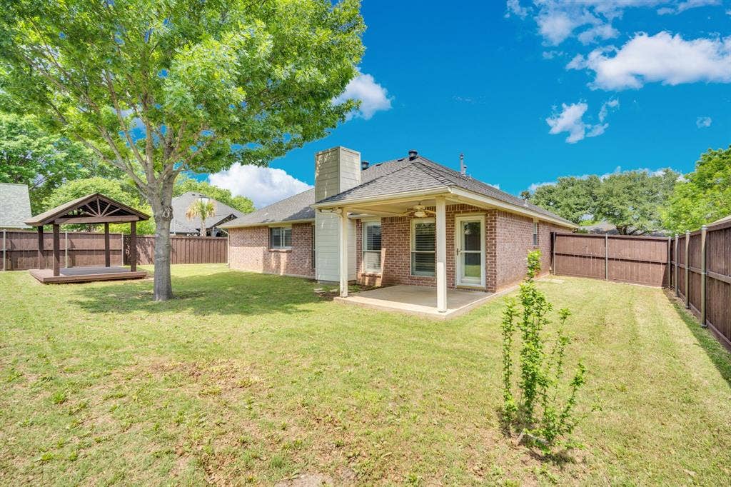 506 Whitney Drive, Midlothian, TX 76065 Expansive backyard featuring a covered patio, a separate gazebo structure with a wood-finish floor, mature trees, and a full privacy fence