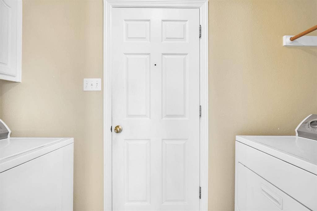 506 Whitney Drive, Midlothian, TX 76065 Utility space featuring an interior six-panel door with brass hardware, light beige painted walls, and built-in white cabinetry