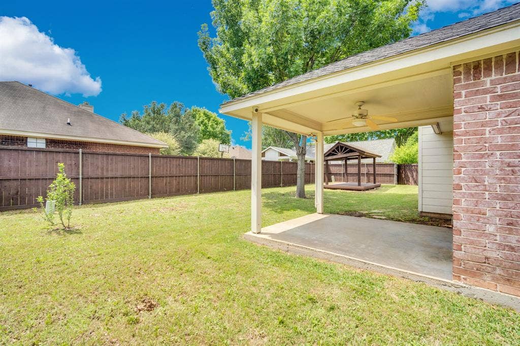 506 Whitney Drive, Midlothian, TX 76065 Spacious backyard featuring a covered patio with a ceiling fan, brick exterior, wood privacy fencing, and a separate wooden gazebo structure
