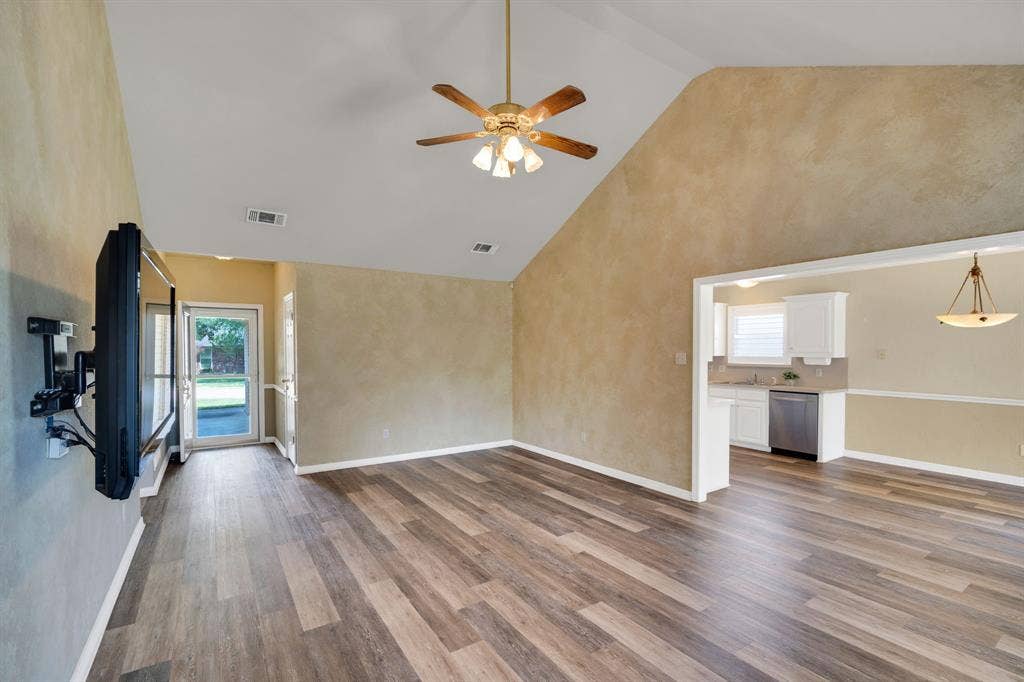 506 Whitney Drive, Midlothian, TX 76065 Open-concept living area featuring wood-finish flooring, a vaulted ceiling with a ceiling fan, and a pass-through opening to the kitchen