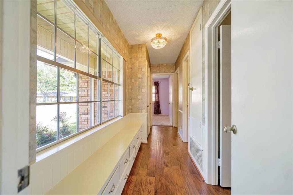 1114 Brookshire Drive, Tyler, TX 75071 Hallway featuring wood-finish flooring, built-in window seating with storage drawers, a large multi-pane window, and a flush mount light fixture