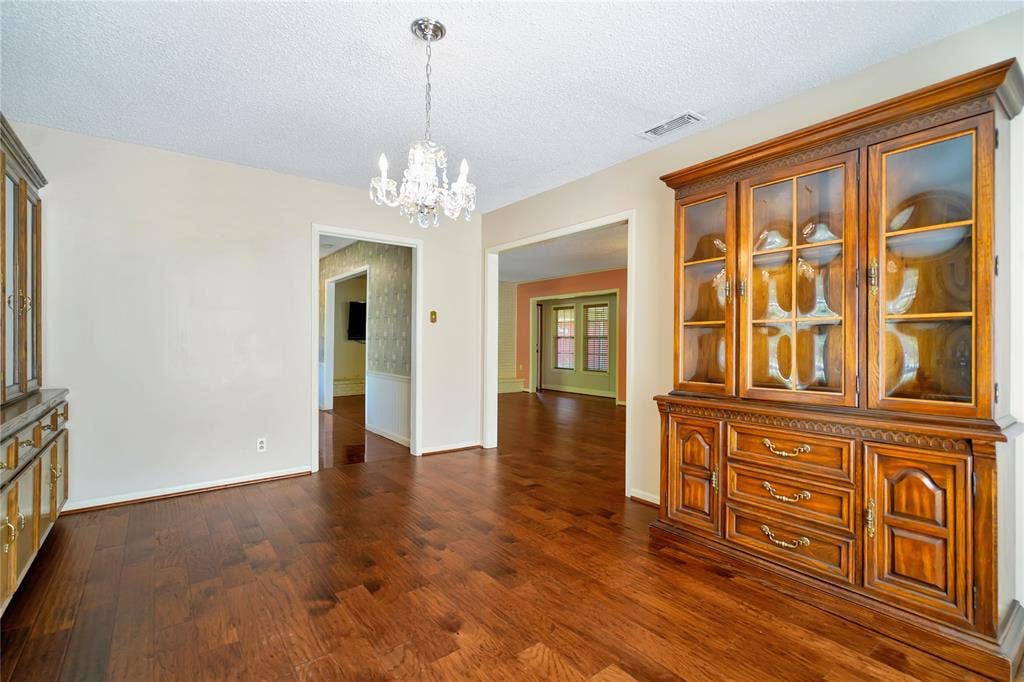 1114 Brookshire Drive, Tyler, TX 75071 Expansive room featuring rich wood-finish flooring, a decorative crystal chandelier, and neutral wall tones