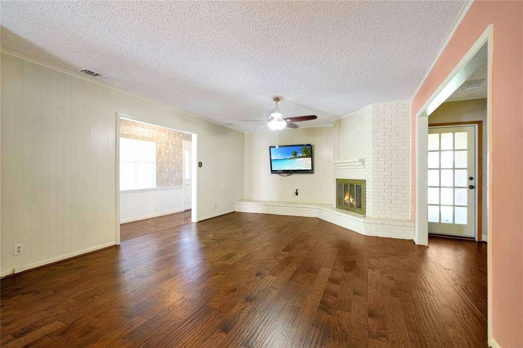 1114 Brookshire Drive, Tyler, TX 75071 Spacious living area featuring wood-finish flooring, a white-painted brick fireplace, and a ceiling fan