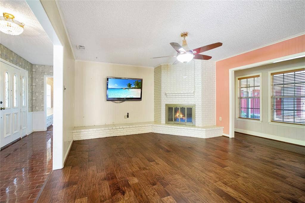 1114 Brookshire Drive, Tyler, TX 75071 Spacious living area featuring wood-finish flooring, a white brick fireplace, and a ceiling fan