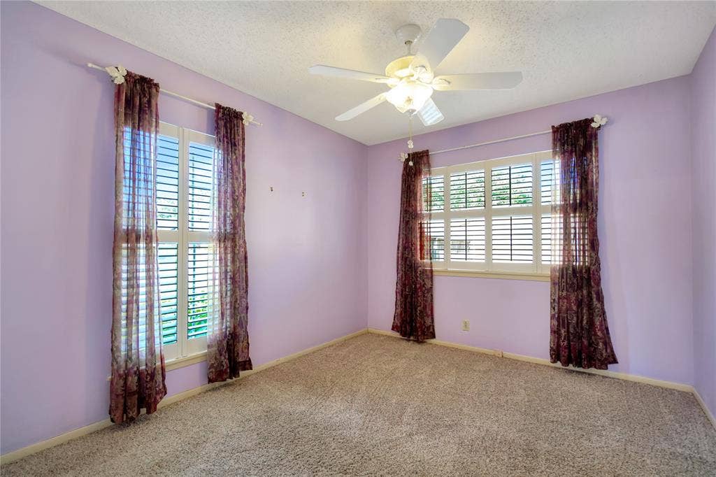 1114 Brookshire Drive, Tyler, TX 75071 Carpeted room featuring two windows with white plantation shutters, a ceiling fan with integrated lighting, and crown molding