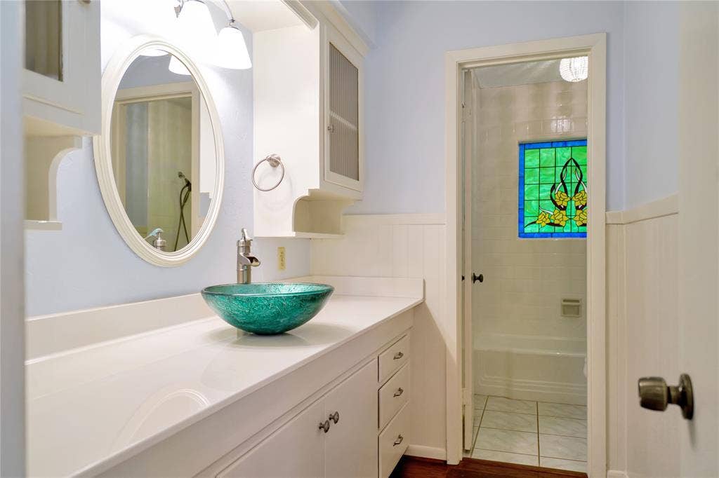 1114 Brookshire Drive, Tyler, TX 75071 Bathroom vanity featuring a glass vessel sink with a brushed nickel faucet, a large oval mirror, and overhead lighting