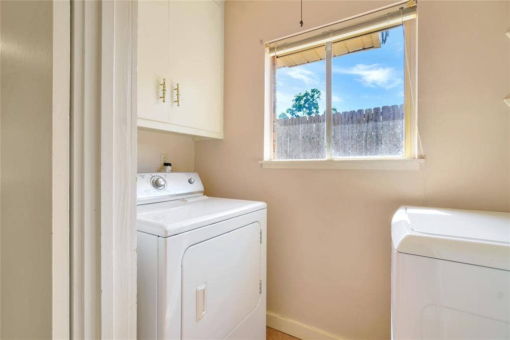 1114 Brookshire Drive, Tyler, TX 75071 Dedicated laundry area featuring a window, overhead cabinetry with brass-toned hardware, and light-toned walls