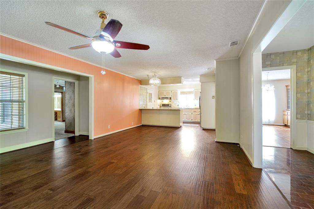 1114 Brookshire Drive, Tyler, TX 75071 Open-concept living space featuring wood-finish flooring, a ceiling fan with integrated lighting, and a breakfast bar with built-in cabinetry