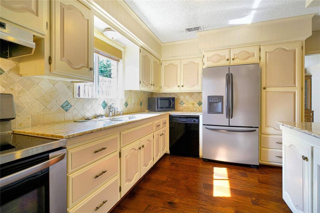 1114 Brookshire Drive, Tyler, TX 75071 Kitchen with wood-finish flooring, light cabinetry, granite-style countertops, stainless steel appliances, and a tiled backsplash