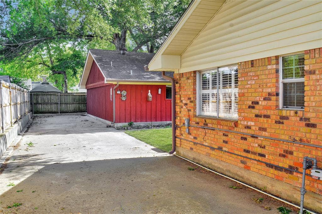 1114 Brookshire Drive, Tyler, TX 75071 Brick exterior with multiple windows, a red-sided accessory building, and a concrete driveway