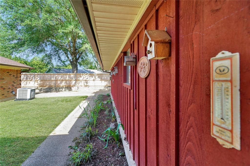 1114 Brookshire Drive, Tyler, TX 75071 Red wood-paneled exterior featuring white soffit, a concrete walkway, and a landscaped garden bed