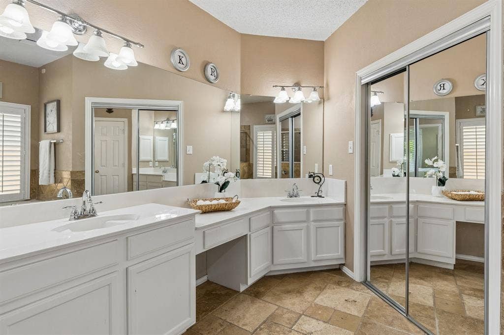 1105 Easton Lane, Allen, TX 75002 The primary bath offers dual vanities connected by a make up area, updated light fixtures and tile flooring.
