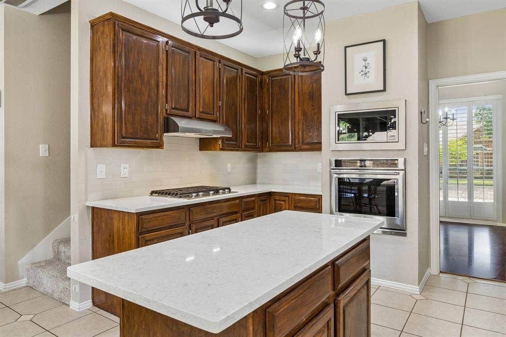 1105 Easton Lane, Allen, TX 75002 The beautifully updated kitchen offers quartz countertops, subway tile backsplash, handsome pendant lighting and direct acess to the dining room. New KitchenAid Microwave 2025, all other appliances 2019.