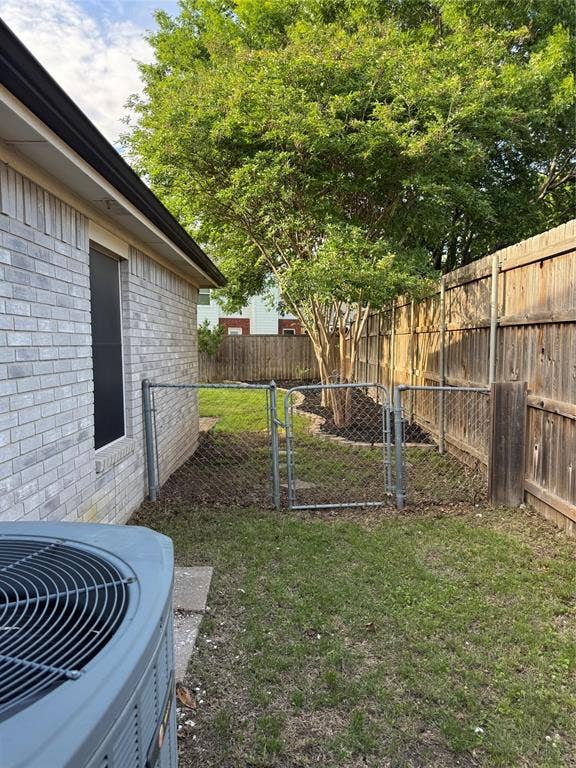 Fenced backyard with mature trees, a chain-link gate, and a wood privacy fence