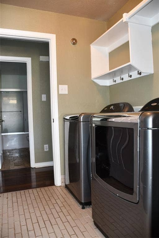 Laundry area featuring brick-patterned tile flooring, a white shelving unit with integrated hooks, and a warm neutral wall color