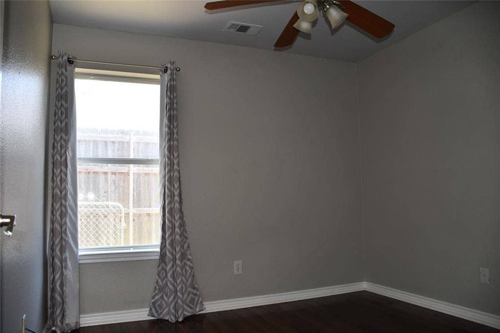 Windowed room featuring wood-finish flooring, light gray walls, and a ceiling fan with integrated lighting