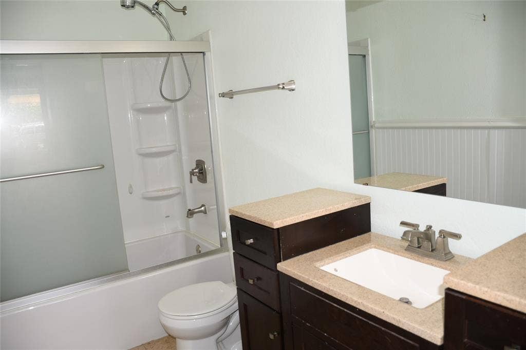 Bathroom featuring a dark wood-finish vanity with an integrated sink, a light-toned countertop, and a large wall-mounted mirror