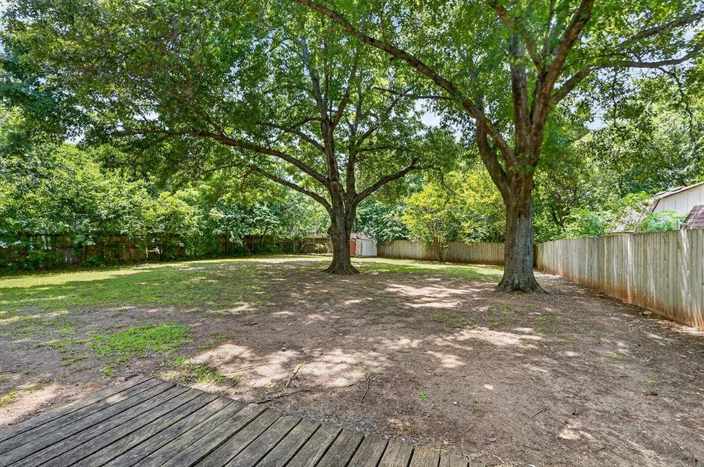 224 Hudson Avenue, Crowley, TX 76036 Expansive backyard featuring mature trees, a wood privacy fence, and a wooden deck