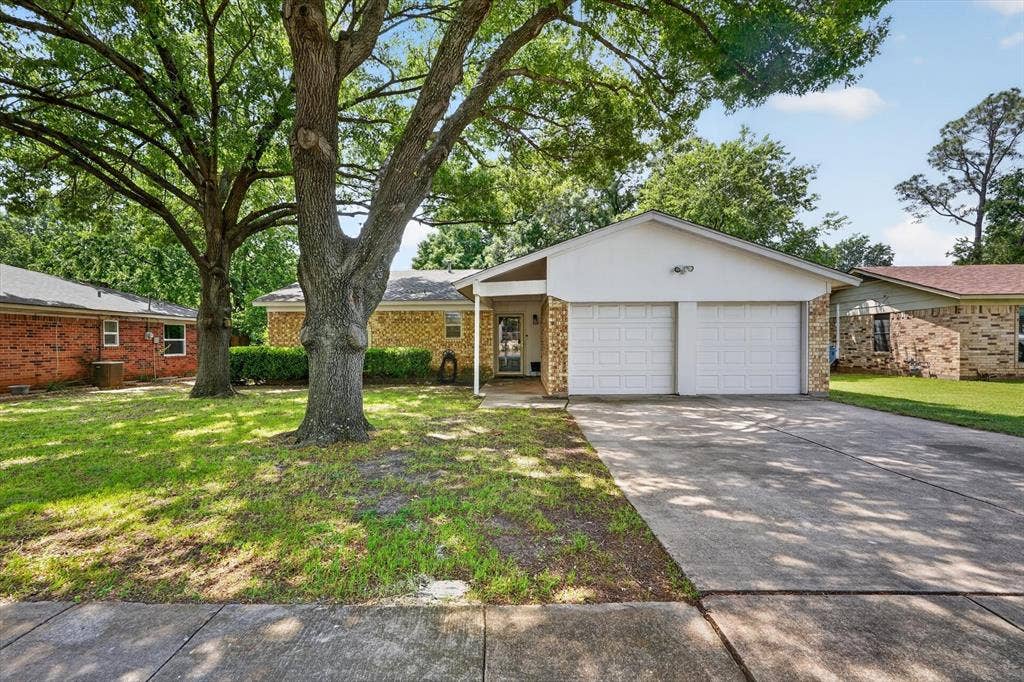 224 Hudson Avenue, Crowley, TX 76036 Single-story residence featuring a two-car garage, brick and stucco exterior, mature front yard trees, and a concrete driveway