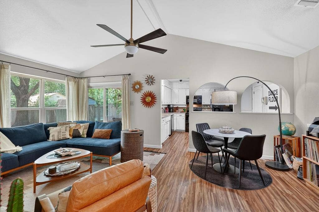 224 Hudson Avenue, Crowley, TX 76036 Vaulted ceiling living area featuring wood-finish flooring, a contemporary ceiling fan, and abundant natural light from multiple windows and a glass slider