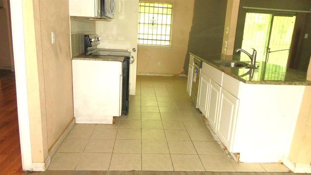 6525 Palm Island Street, Dallas, TX 75241 Kitchen featuring tile flooring, white cabinetry, a built-in stainless steel dishwasher, and a sink with a gooseneck faucet