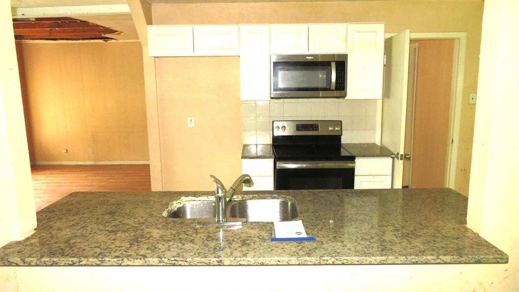 6525 Palm Island Street, Dallas, TX 75241 Kitchen featuring white cabinetry, stainless steel microwave, black electric range, and granite countertops