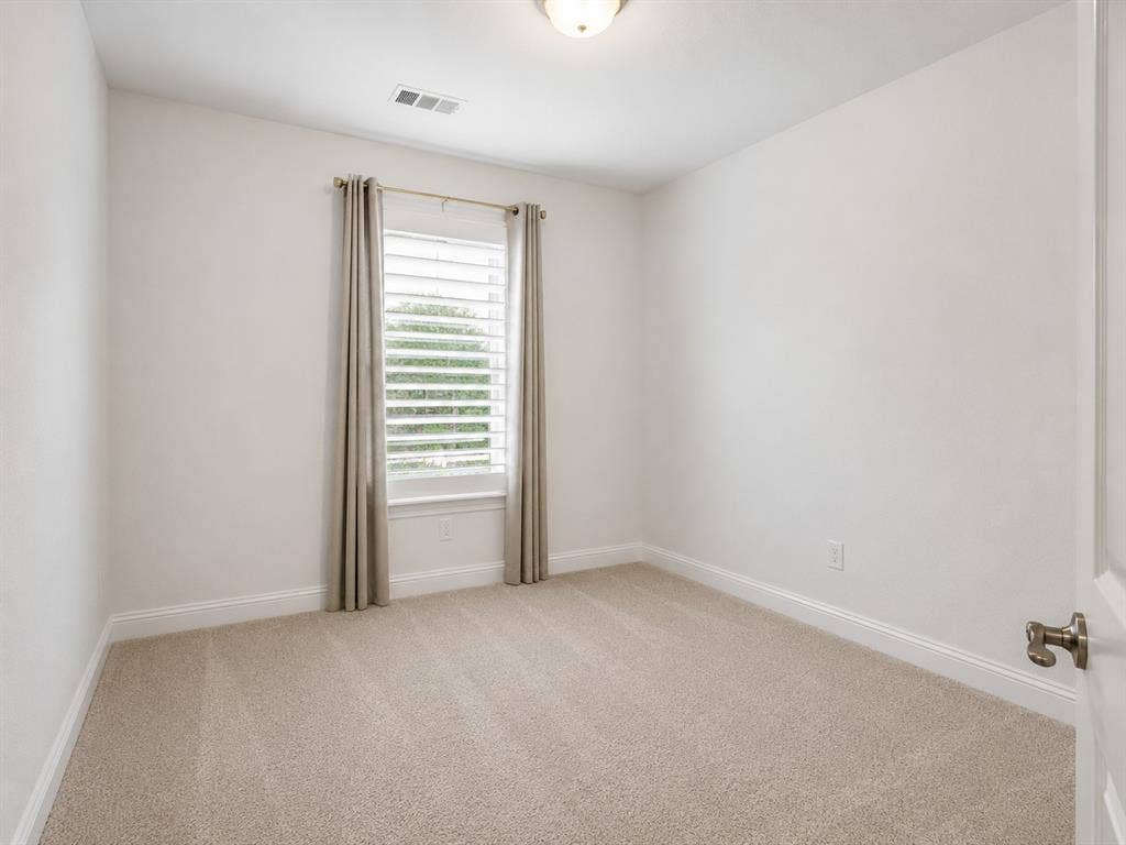 Carpeted room featuring a single window with plantation shutters, surrounded by drapes. This image has been virtually enhanced for marketing purposes.