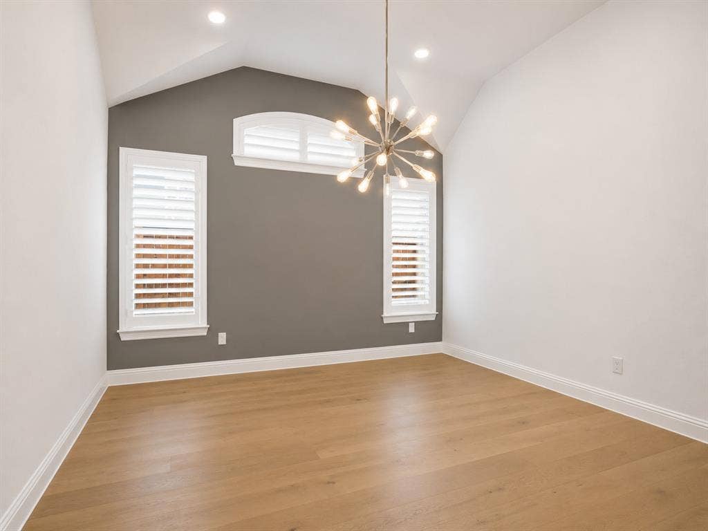 Vaulted ceiling room featuring light wood-finish flooring, recessed lighting, and a contemporary chandelier