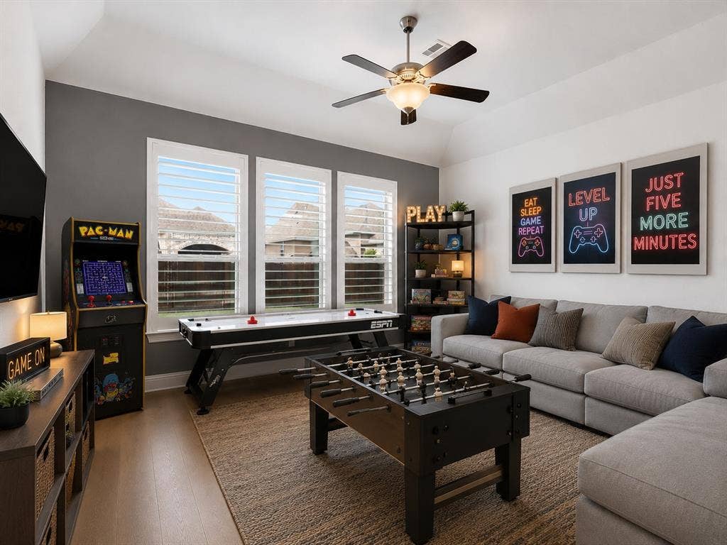 Spacious entertainment room featuring wood-finish flooring, three large windows with plantation shutters, a ceiling fan, and recessed lighting. This image has been virtually enhanced for marketing purposes.