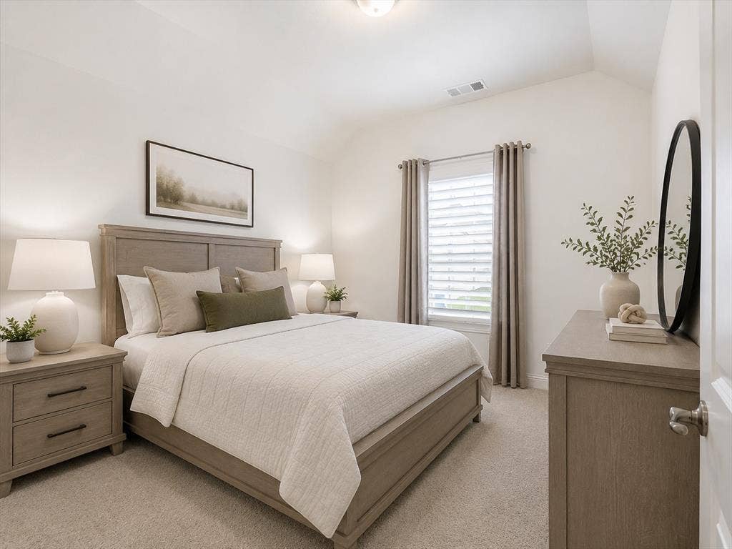 Spacious bedroom featuring light neutral wall tones, textured carpeting, a window with plantation shutters and drapes, and a vaulted ceiling. This image has been virtually enhanced for marketing purposes.