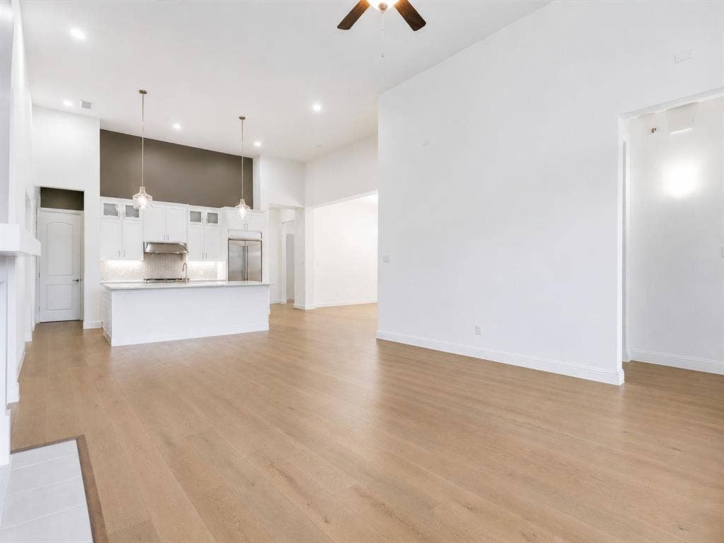 Open-concept living area with wood-finish flooring, vaulted ceilings, and recessed lighting