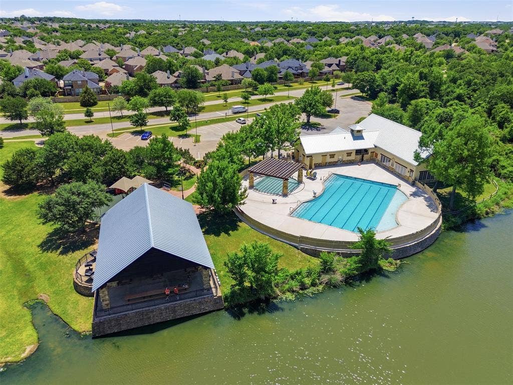 Community recreation complex featuring a large swimming pool, expansive pool deck, and a shaded pergola