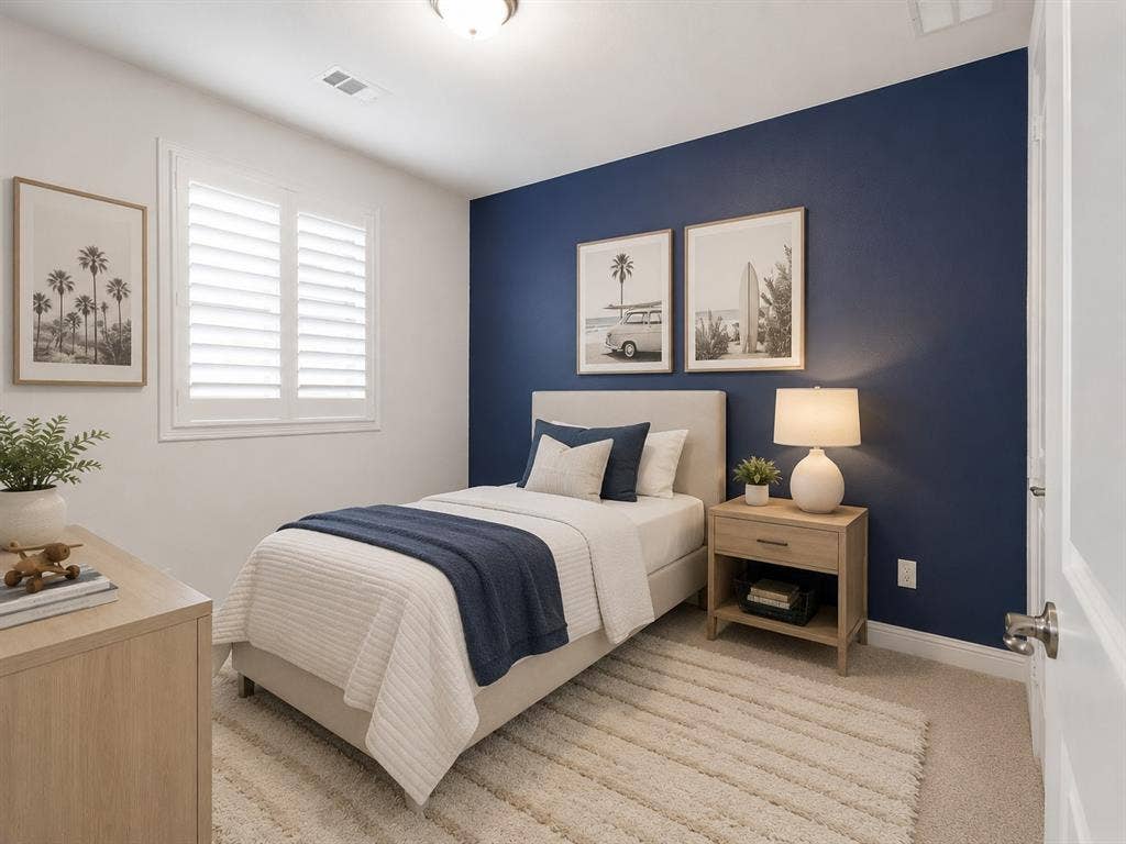Bedroom featuring a window with white louvered shutters, a neutral-toned upholstered bed frame, and light-toned wood-finish furniture. This image has been virtually enhanced for marketing purposes.