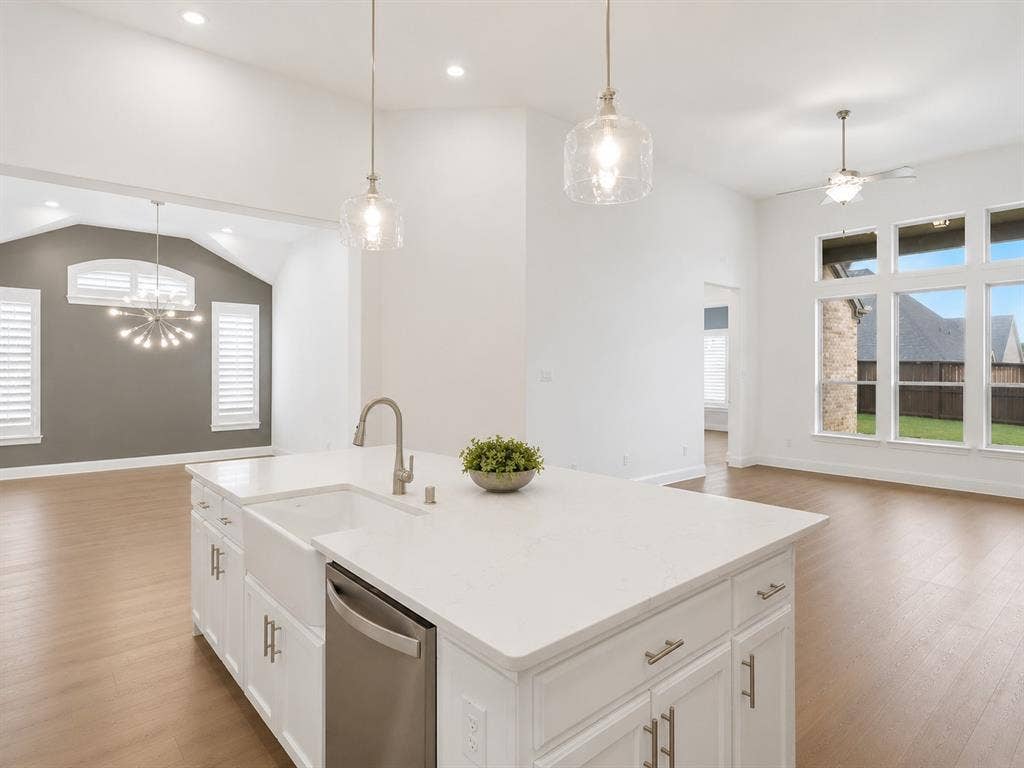 Kitchen island featuring a farmhouse sink and integrated dishwasher, complemented by quartz countertops and pendant lighting. This image has been virtually enhanced for marketing purposes.