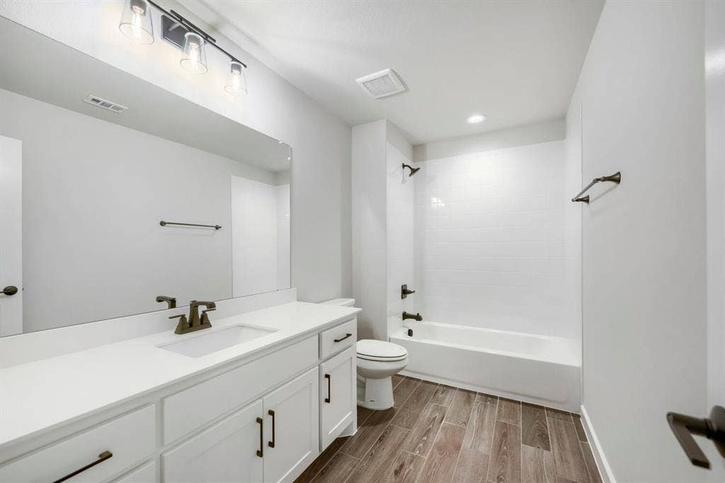 800 Blackberry Road, Haslet, TX 76052 Bathroom featuring a white vanity with integrated sink, white cabinetry, dark bronze hardware, and wood-finish flooring
