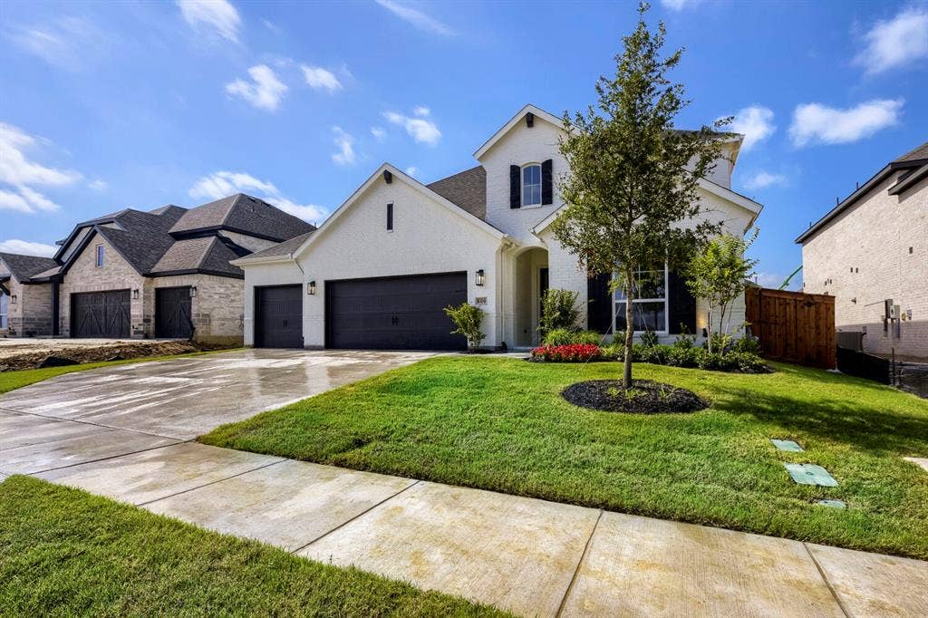 800 Blackberry Road, Haslet, TX 76052 Modern white brick residence featuring a dark gray roof, black garage doors, and a manicured lawn