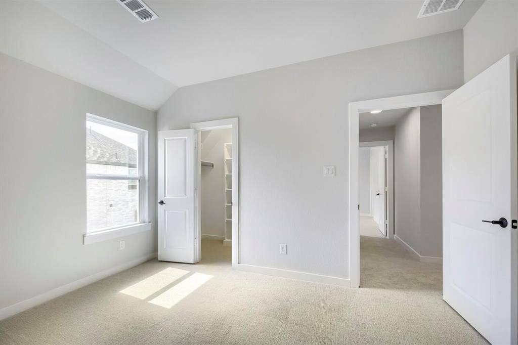 800 Blackberry Road, Haslet, TX 76052 Vaulted ceiling bedroom with light-toned carpet flooring, a double-hung window, and a walk-in closet featuring shelving