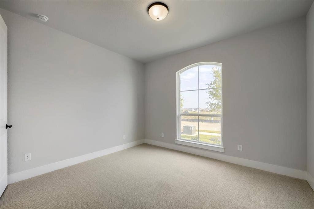 800 Blackberry Road, Haslet, TX 76052 Room featuring a large arched window with grid-patterned panes, light gray wall tones, neutral carpeting, and white baseboards