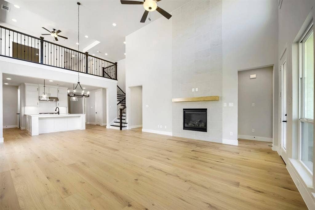 800 Blackberry Road, Haslet, TX 76052 Spacious living area featuring high ceilings, wood-finish flooring, and a modern fireplace with a light wood mantel