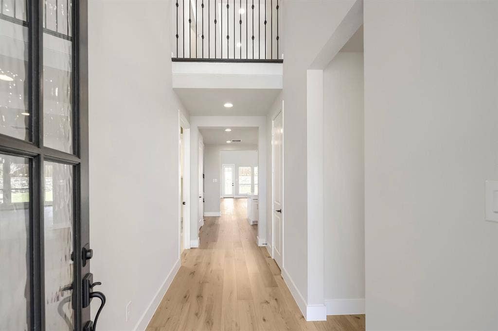 800 Blackberry Road, Haslet, TX 76052 Foyer featuring a two-story ceiling, wood-finish flooring, a contemporary iron and glass entry door, recessed lighting, and a second-story overlook with an iron balustrade