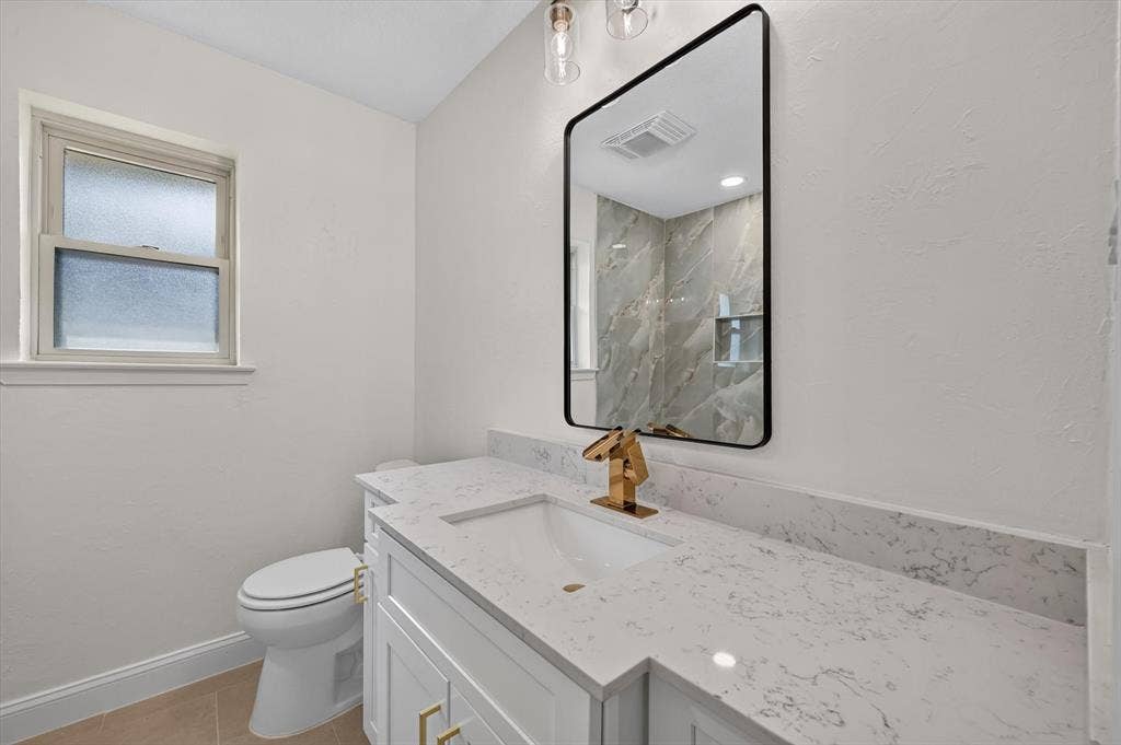 3420 Denbury Drive, Fort Worth, TX 76133 Bathroom vanity featuring a quartz countertop with an integrated sink, gold-finish faucet, and coordinating gold-tone cabinet hardware